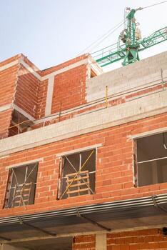 detallado ver de un edificio debajo construcción, exhibiendo rojo ladrillo paredes con inconcluso aberturas y secundario vigas, destacando el en marcha arquitectónico proceso. vertical fotografía. foto