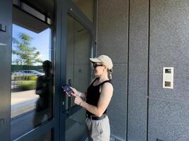 Close up of woman using intercom at building entrance. photo