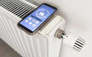 Adjusting Temperature Of Digital Smart Thermostat Using Mobile Phone App At Home photo