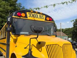 Shot of retro-styled yellow school bus with extended red stop sign standing still on serene road, empty vehicle with no driver awaiting children to boarding, transportation concept, copy space photo