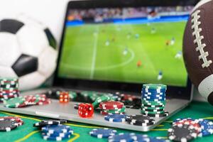 Close up cropped shot of male hands making bets using gambling mobile application on his phone. Man watching football match online broadcast on his laptop waiting for winning results. photo