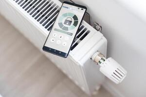 Adjusting Temperature Of Digital Smart Thermostat Using Mobile Phone App At Home photo