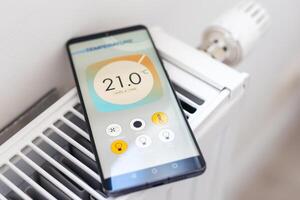Controlling radiator heating temperature with a smart phone, close-up with radiator on the background. Concept of a smart home and mobile application for managing smart devices at home photo