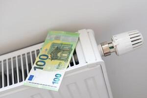 Calculator and fifty euro banknotes lie on the radiator of the heating system, the cost of heat, utility bills photo