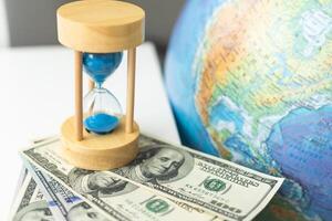 Wooden egg timer alongside a world globe or earth in a concept of running out of time to save the planet from pollution and destruction of the ecology photo