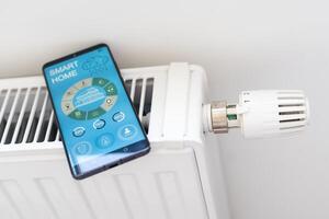 Controlling radiator heating temperature with a smart phone, close-up with radiator on the background. Concept of a smart home and mobile application for managing smart devices at home photo