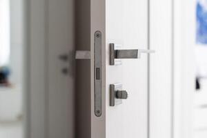 Modern white door with matte black handle and magnetic locks, lock with insert key. photo