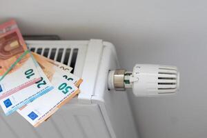 Calculator and fifty euro banknotes lie on the radiator of the heating system, the cost of heat, utility bills photo