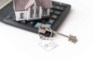 House over white with calculator and house keys. photo