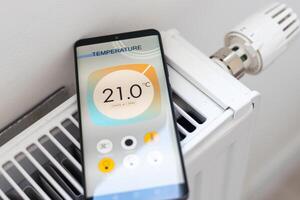Adjusting Temperature Of Digital Smart Thermostat Using Mobile Phone App At Home photo