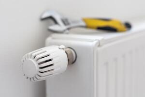 tightens the nut on the radiator with an adjustable wrench photo