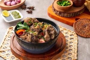sop buntut or oxtail soup. Made from pieces of beef tail that are seasoned then put in a slightly beef broth with sliced potatoes, carrots, tomatoes, celery. Indonesian traditional culinary photo