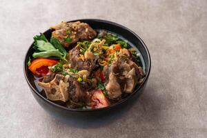 sop buntut or oxtail soup. Made from pieces of beef tail that are seasoned then put in a slightly beef broth with sliced potatoes, carrots, tomatoes, celery. Indonesian traditional culinary photo