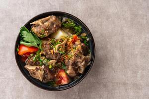 sop buntut or oxtail soup. Made from pieces of beef tail that are seasoned then put in a slightly beef broth with sliced potatoes, carrots, tomatoes, celery. Indonesian traditional culinary photo