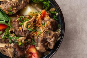 sop buntut or oxtail soup. Made from pieces of beef tail that are seasoned then put in a slightly beef broth with sliced potatoes, carrots, tomatoes, celery. Indonesian traditional culinary photo