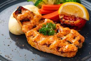 Grilled salmon fillets with mentai sauce and mash potato plating on black plate with negative space for text. photo