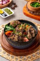 sop buntut or oxtail soup. Made from pieces of beef tail that are seasoned then put in a slightly beef broth with sliced potatoes, carrots, tomatoes, celery. Indonesian traditional culinary photo