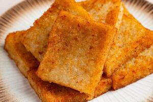 Turnip cake or Chai tow kway. Turnip cake is a common dish or dim sum of Teochew cuisine in Chaoshan, China usually cut into rectangular slices and sometimes pan fried before serving photo