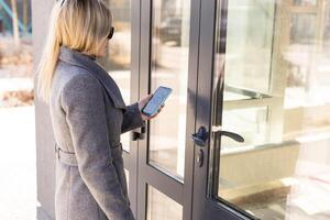 Woman locking smartlock on the entrance door using a smart phone. Concept of using smart electronic locks with keyless access photo