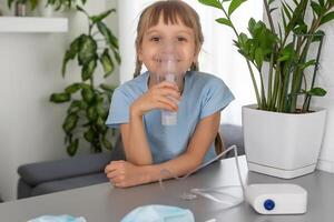 sick little girl makes inhalation over grey background with copy space. Girl making inhalation with nebulizer at home. child asthma inhaler inhalation nebulizer steam sick cough photo
