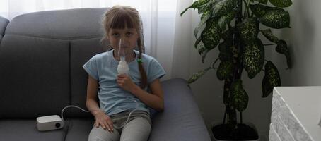 Little girl making inhalation with nebulizer at home. child asthma inhaler inhalation nebulizer steam sick cough concept. photo