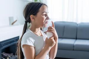 sick little girl makes inhalation over grey background with copy space. Girl making inhalation with nebulizer at home. child asthma inhaler inhalation nebulizer steam sick cough photo