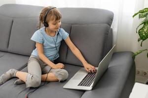 Back view of young girl sit at home, talk have online call lesson with teacher or tutor, teenage schoolgirl engaged in webcam conversation, study distant use web conference app on laptop photo