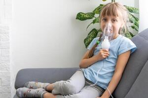 Little girl making inhalation with nebulizer at home. child asthma inhaler inhalation nebulizer steam sick cough concept. photo