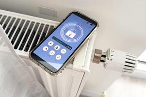 Adjusting Temperature Of Digital Smart Thermostat Using Mobile Phone App At Home photo