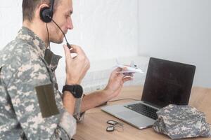 Military Technical Service, Air Force Concept. Hands of a man in uniform holding a silver toy airplane. A middle-aged adult man in a green camouflage uniform. Indoors. photo