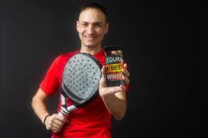 man holding paddel racket and smartphone with bet black background photo