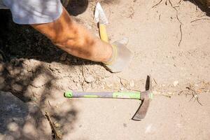 arm of an archeologist in an archeological excavation on the side of the floor there are two tools, a small pickaxe and a trowel. photo