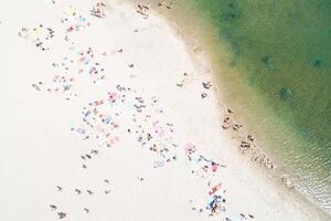 people on the shore of a beach enjoying the summer, aerial overhead view with a drone. photo