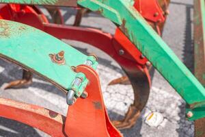 close up view of a red and green plow with signs of rusting photo