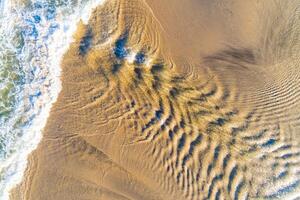 zenithal aerial drone view of wave flows on a beach shore in summer photo