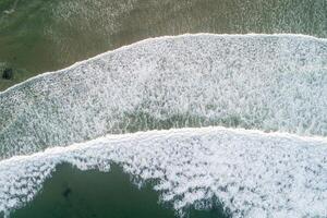 Aerial top view of turquoise ocean creating patterns in the sand at sunset photo