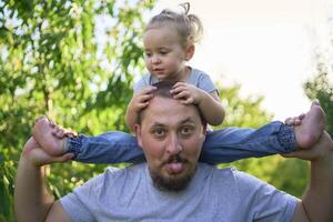 a father plays with a toddler on his shoulders photo