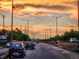Cars driving on a road at sunset with power lines photo