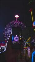 A person taking a photo of a ferris wheel at night