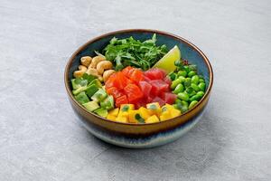 Top view of a colorful salmon poke bowl with fresh vegetables and rice, presented photo