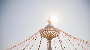 Decorative strings of beads hanging from a white structure against a clear blue sky photo