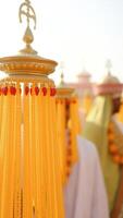 Close-up of ornate gold tassels with red beads in the foreground, with blurred figures and additional tassels in the background photo