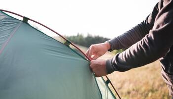 Close-up of a person setting up a tent in a grassy field photo