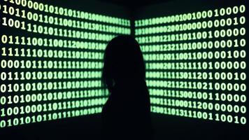 Silhouette of a person in front of a wall of binary code photo