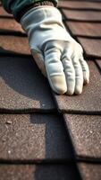 Close Up Of Gloved Hand Installing Asphalt Shingles On A Roof photo