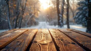 Empty wooden table with falling snow and winter forest background illuminated by the setting sun photo
