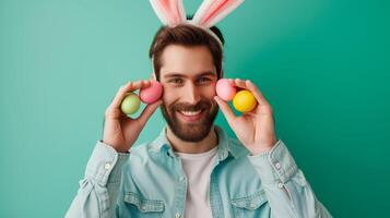Happy man in cute bunny ears headband holding Easter eggs on light green background. Creative banner for celebration of Easter. photo