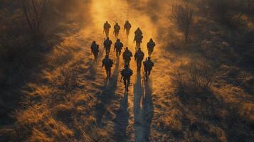 Military platoon marches across a desolate desert terrain as the sun sets, creating elongated shadows photo