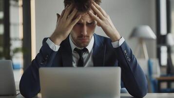 Young professional is experiencing fatigue and a headache while working on his laptop in the office photo
