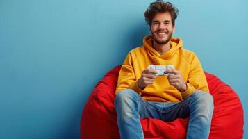 Young man enjoys playing games, holding a controller while sitting on a red beanbag chair photo